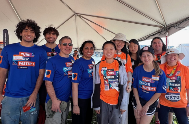 Group photo of people under outdoor tent wearing blue and orange Obliteride shirts